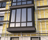 Scaffolding surrounding a modern residential building undergoing thermal insulation and exterior renovation.